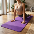 COLOUR:Purple - yoga mat unrolled on a wooden floor with a person mid-pose