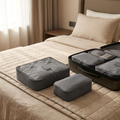 Grey packing cube set on a hotel bed beside a suitcase