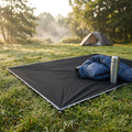 Black waterproof camping mat spread on grass at a campsite