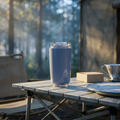 Insulated travel cup on a camp table at sunrise