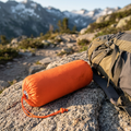 Orange emergency sleeping bag rolled beside a hiking pack