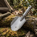 Titanium camping trowel on a mossy log at a bush campsite