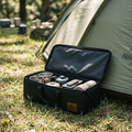 Black folding camping storage box open beside a tent